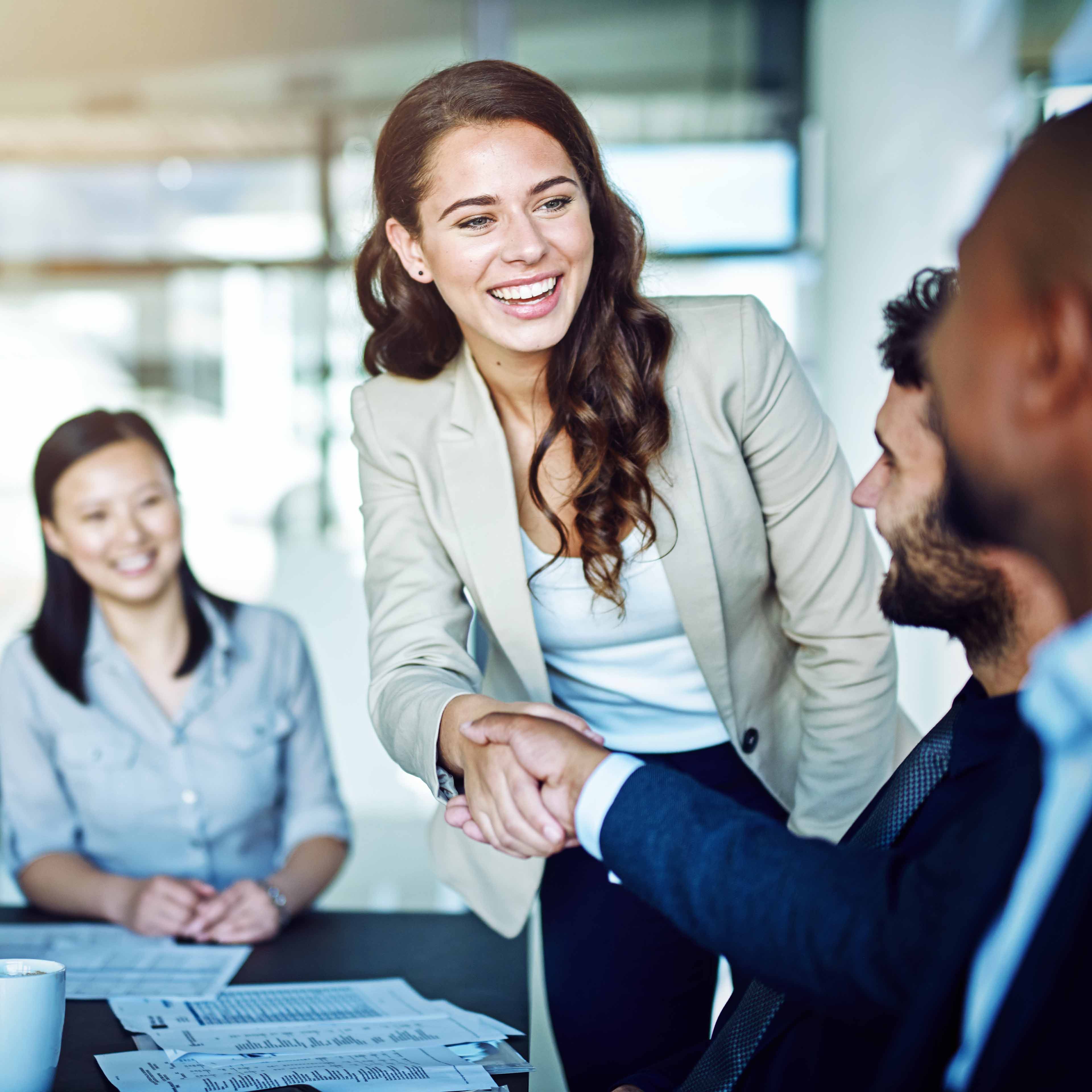 Smiling work colleagues around a table shaking hands
